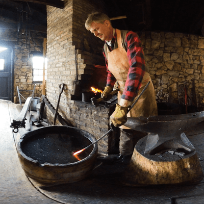 A blacksmith cooling a hot rod