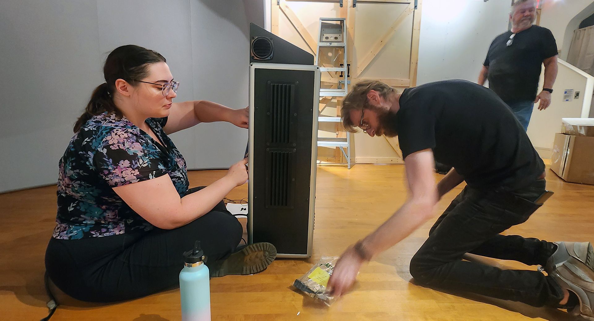 a man and woman work on projector systems