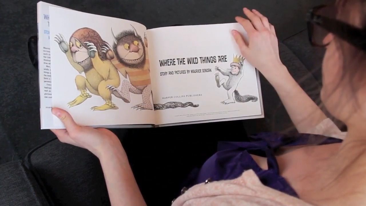 A girl is reading a book with cartoon characters.
